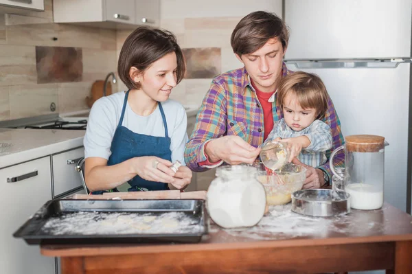 Jovem família preparando massa para biscoitos juntos — Fotografia de Stock