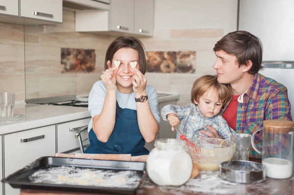 Jovem família preparando biscoitos caseiros em forma de corações — Fotografia de Stock