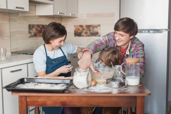 Juguetona familia joven preparando galletas juntos en la cocina - foto de stock