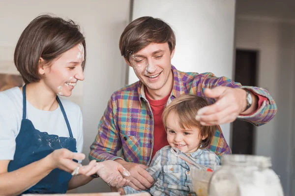 Счастливые молодые родители и восхитительный маленький ребенок, играющий с полом на кухне — стоковое фото