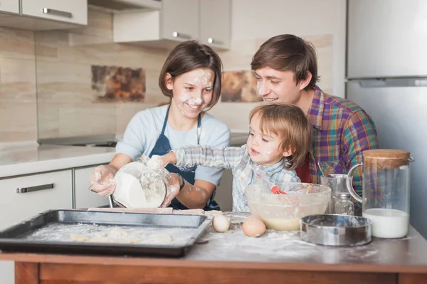 Little child helping his parents with cooking at kitchen — Stock Photo
