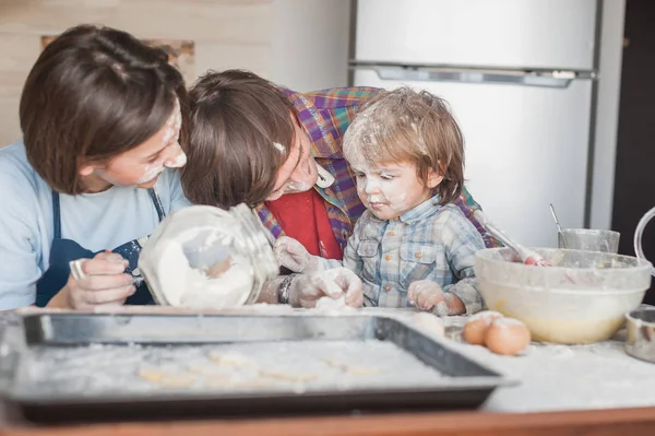Красивая молодая семья проливается мукой проводить время вместе на кухне — стоковое фото