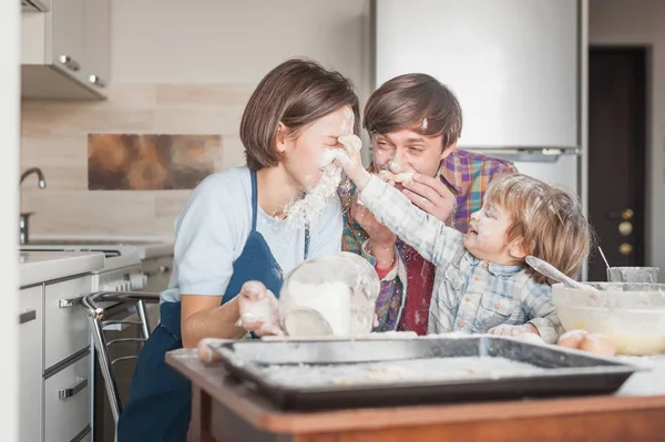 Счастливая молодая семья веселится с мукой на кухне во время выпечки — стоковое фото