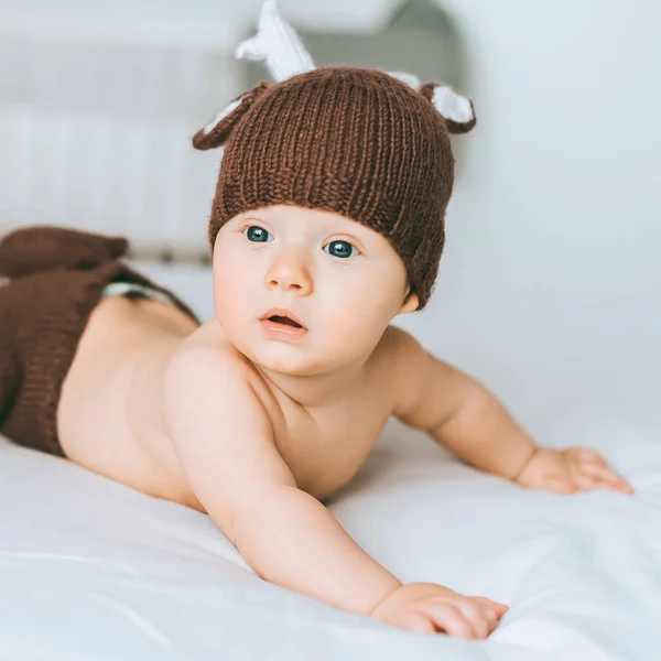 Close-up retrato de criança adorável bebê em traje de veado de malha na cama — Fotografia de Stock