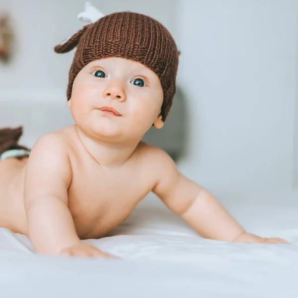 Close-up shot of beautiful infant child in knitted deer hat in bed — Stock Photo