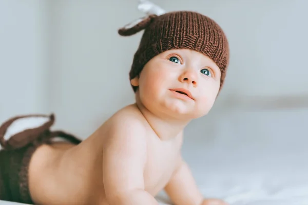 Retrato de primer plano del niño en pantalones cortos de punto y sombrero mirando hacia arriba en la cama - foto de stock