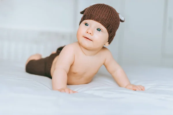 Smiling infant child in beautiful knitted deer costume in bed — Stock Photo