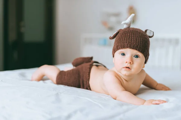 Adorable enfant en bas âge en costume de cerf tricoté au lit — Photo de stock