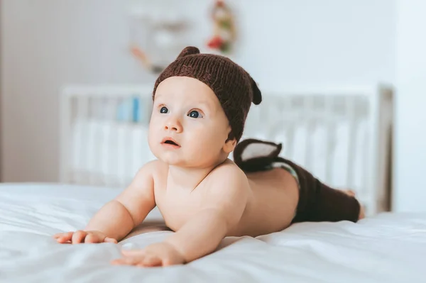 Criança infantil expressa em shorts de veado de malha e chapéu na cama — Fotografia de Stock