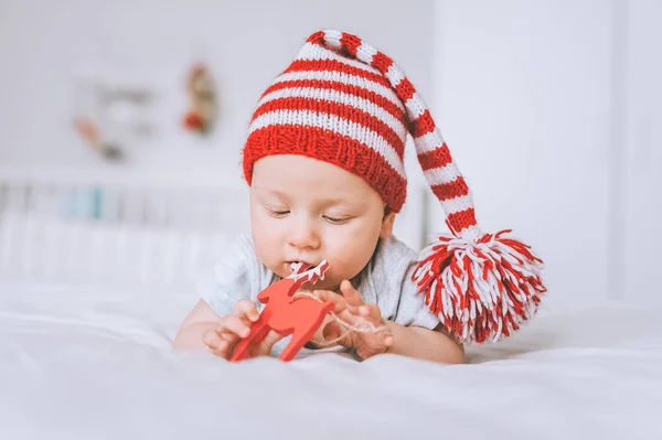 Bambino neonato che gioca con la decorazione dei cervi giocattolo a letto — Foto stock