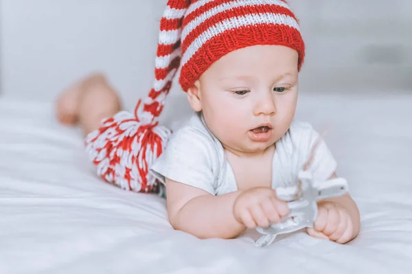 Возбужденный младенец играет с игрушечным украшением оленя в постели — стоковое фото