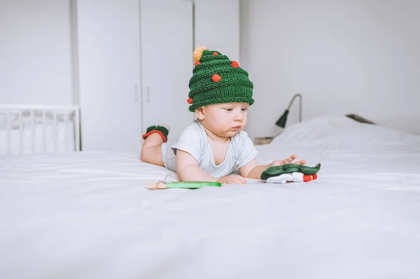 Infant child in adorable christmas tree knitted hat in bed — Stock Photo