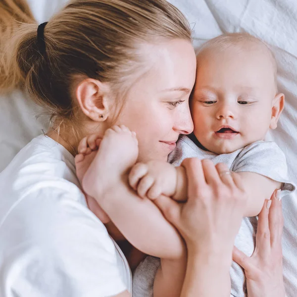 Nahaufnahme einer jungen Mutter, die ihr Kleinkind im Bett umarmt — Stockfoto