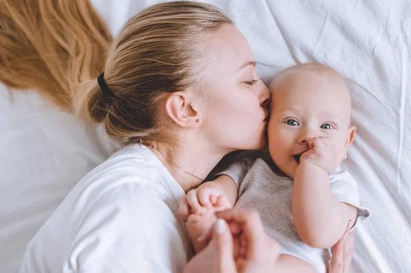 Top view of mother kissing her infant baby in bed — Stock Photo