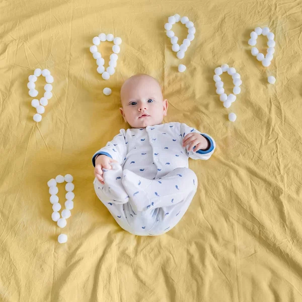 Vue de dessus du nourrisson entouré de points d'exclamation faits de boules de coton au lit — Photo de stock