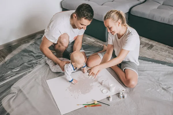 Visão de alto ângulo de feliz jovem família com bela criança pequena pintura juntos no chão em casa — Fotografia de Stock