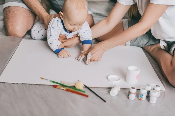 Cropped shot of young family with beautiful infant child painting together on floor — Stock Photo