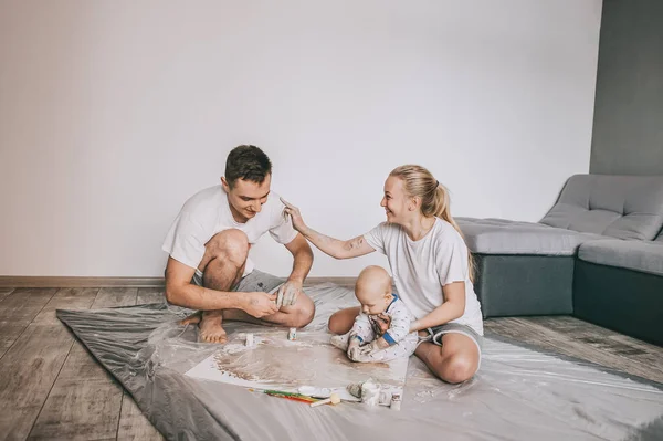 Bella felice giovane famiglia con adorabile bambino bambino pittura insieme a casa — Foto stock