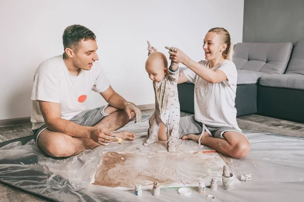 Schöne glückliche junge Familie mit entzückendem Kleinkind, das gemeinsam auf dem Fußboden malt — Stockfoto