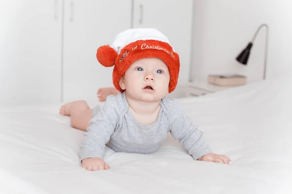 Ritratto di bambino piccolo in cappello di Babbo Natale sdraiato sul letto — Foto stock