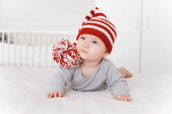 Retrato de niño hermoso en sombrero de punto acostado en la cama - foto de stock