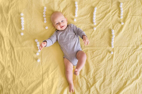 Vista dall'alto del bambino bambino divertente sdraiato circondato da punti esclamativi fatti di batuffoli di cotone a letto — Foto stock