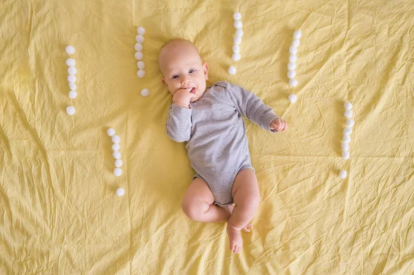Top view of adorable infant surrounded with exclamation marks made of cotton balls in bed — Stock Photo