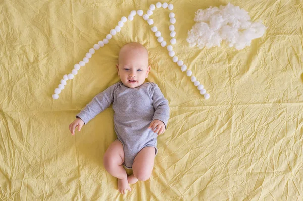 Top view of adorable child under house roof made of cotton balls and cotton cloud on bed — Stock Photo