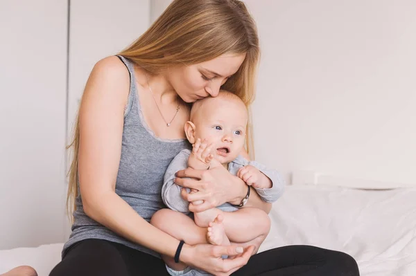Schöne junge Mutter umarmt und küsst entzückendes Kleinkind — Stockfoto