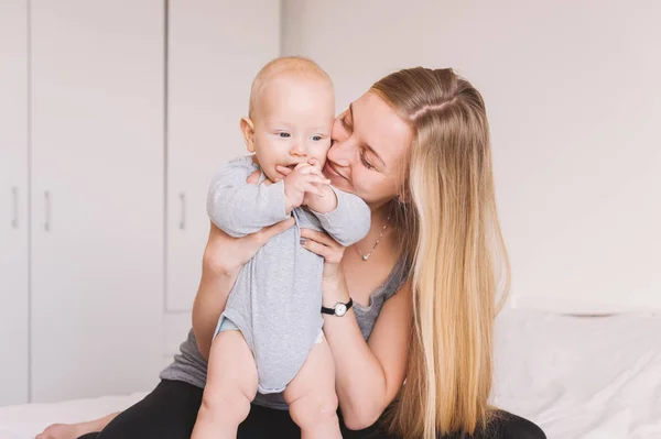 Щаслива молода мати обіймає і цілує чарівну дитину — стокове фото