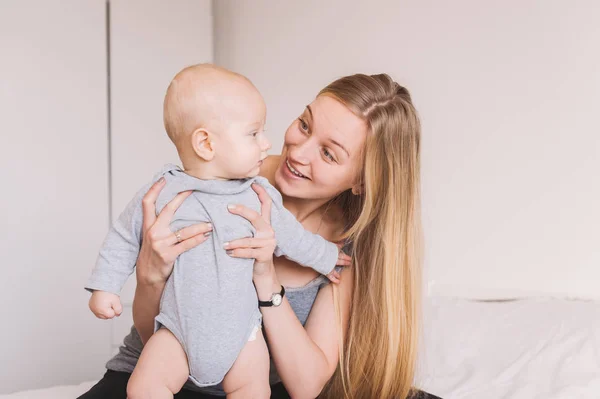 Beautiful young mother hugging and lookign at adorable infant child — Stock Photo