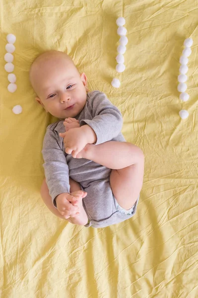 Vista superior del niño rodeado de signos de exclamación hechos de bolas de algodón en la cama - foto de stock