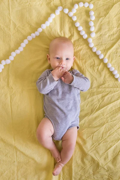 Vue de dessus du beau bébé enfant sous le toit de la maison en boules de coton au lit — Photo de stock