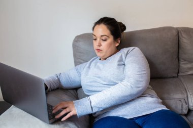 Kanepede bilgisayara bakan kız rahatlamış.