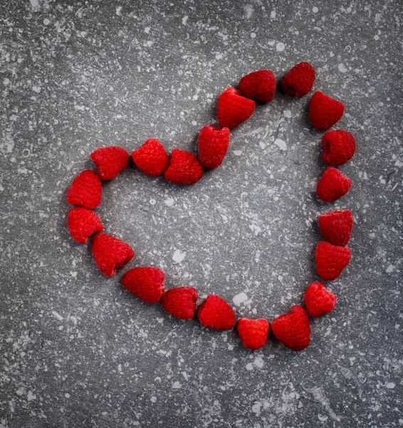 Raspberries in a heart shape on a stone background — Stock Photo, Image