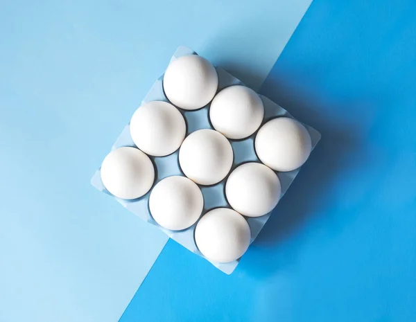 Oeufs de poulet crus blancs sur fond bleu coloré — Photo