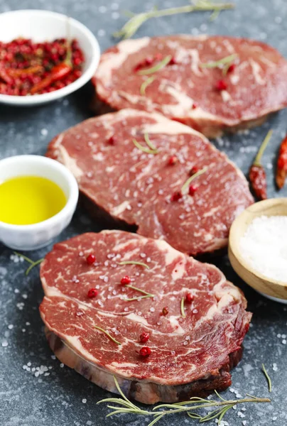 Carne fresca cruda Ribeye Bistecca con rosmarino, pepe e sale marino o — Foto Stock