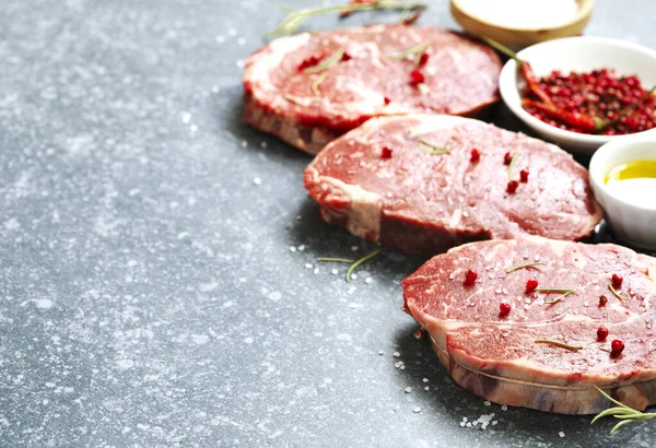 Surowe świeże mięso Ribeye Steak z rozmarynu, pieprzu i soli morskiej o — Zdjęcie stockowe