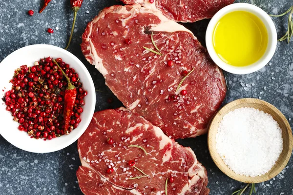Surowe świeże mięso Ribeye Steak z rozmarynu, pieprzu i soli morskiej o — Zdjęcie stockowe