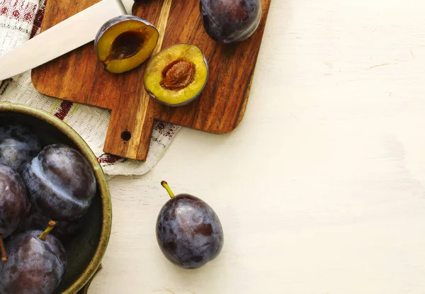 Fresh plums in bowl on wooden table, top view — Stock Photo, Image