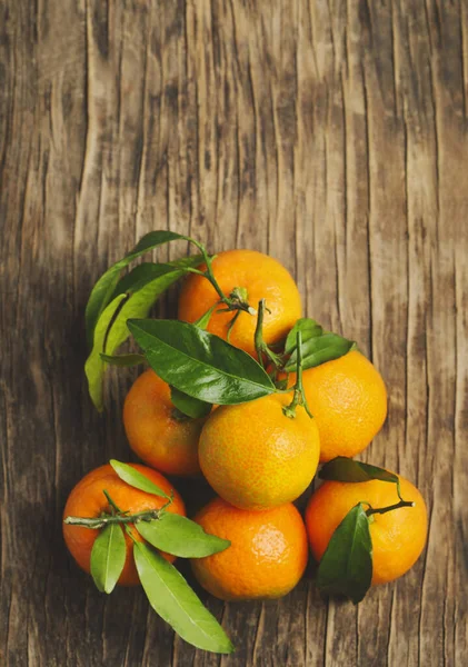 Mandarijnen met groene bladeren op houten achtergrond — Stockfoto