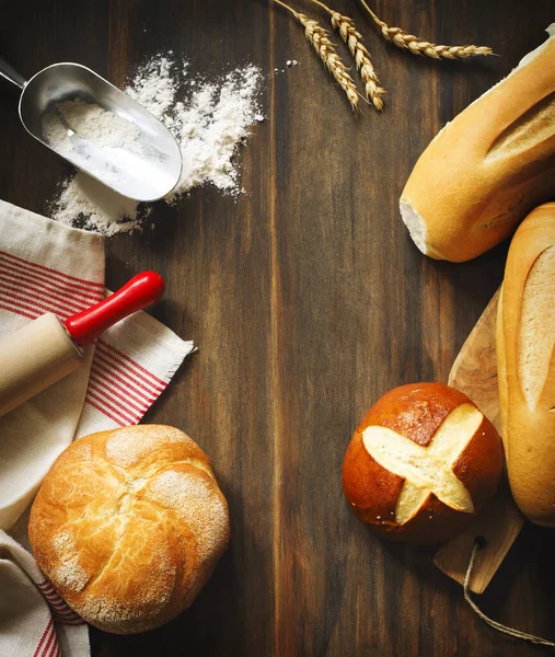 Assortment of baked bread, flour and roller pin on wooden backgr — Stock Photo, Image
