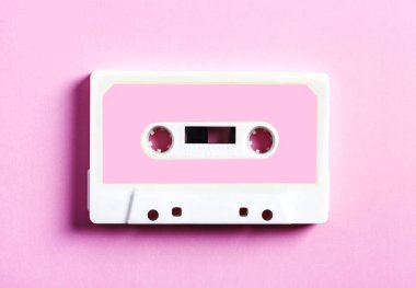 Pink retro cassette tape on pink background, top view.