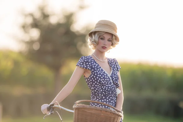 Blond kvinna med cykel i landsbygdens landskap — Stockfoto