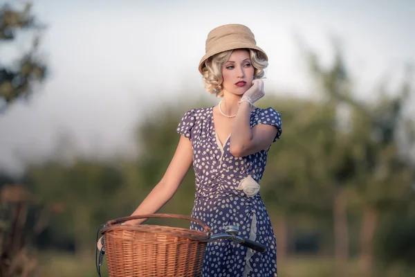 Mujer rubia con bicicleta en el paisaje rural — Foto de Stock