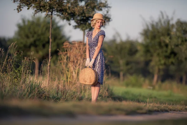 Mujer rubia con bolso en camino rural — Foto de Stock
