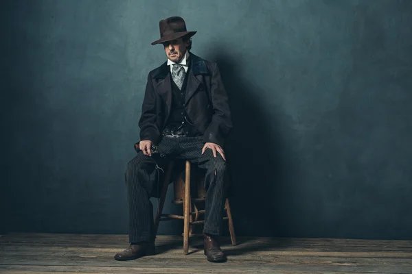 Homme mûr avec revolver assis sur tabouret — Photo