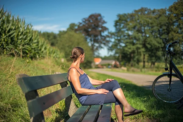 Kvinnlig cyklist vilar på bänk — Stockfoto