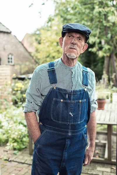 Vintage senior farmer wearing dungarees — Stock Photo, Image