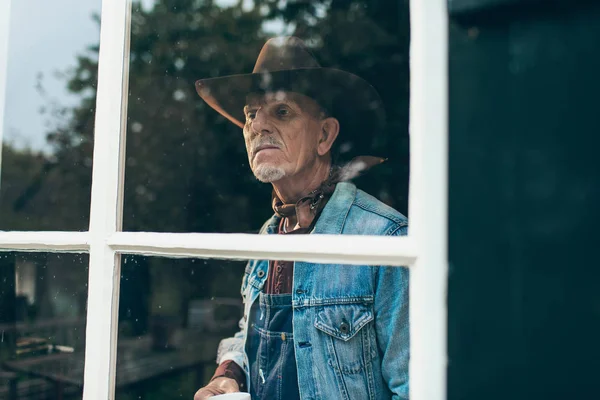 Farmer looking out window of old farm — Stock Photo, Image